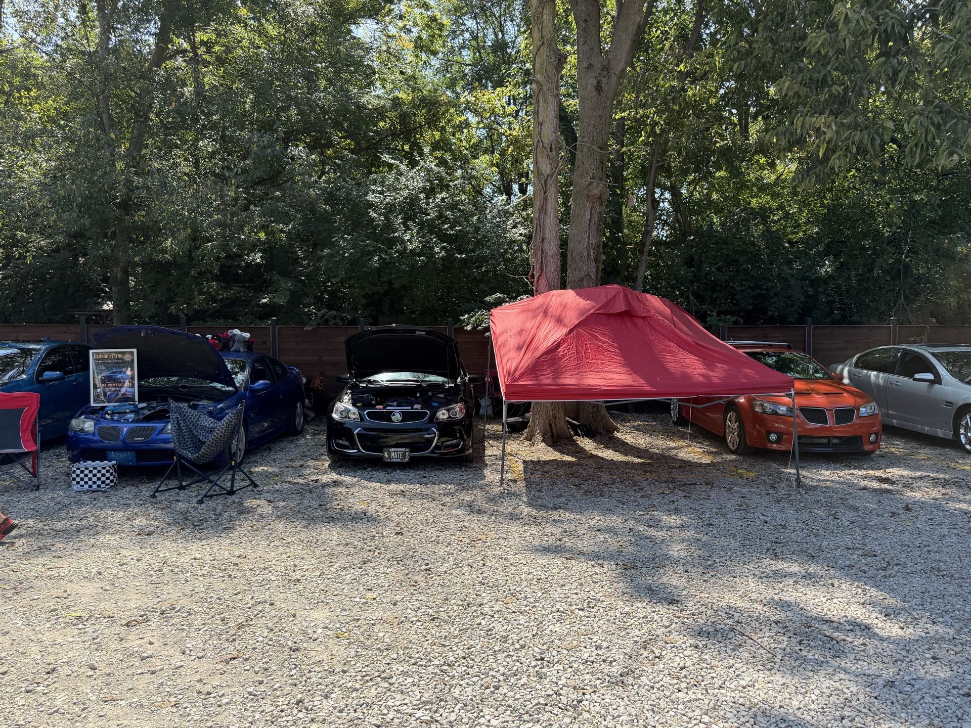 Chevy SS parked with hood up alongside other Holdens and Pontiacs under a red canopy tent